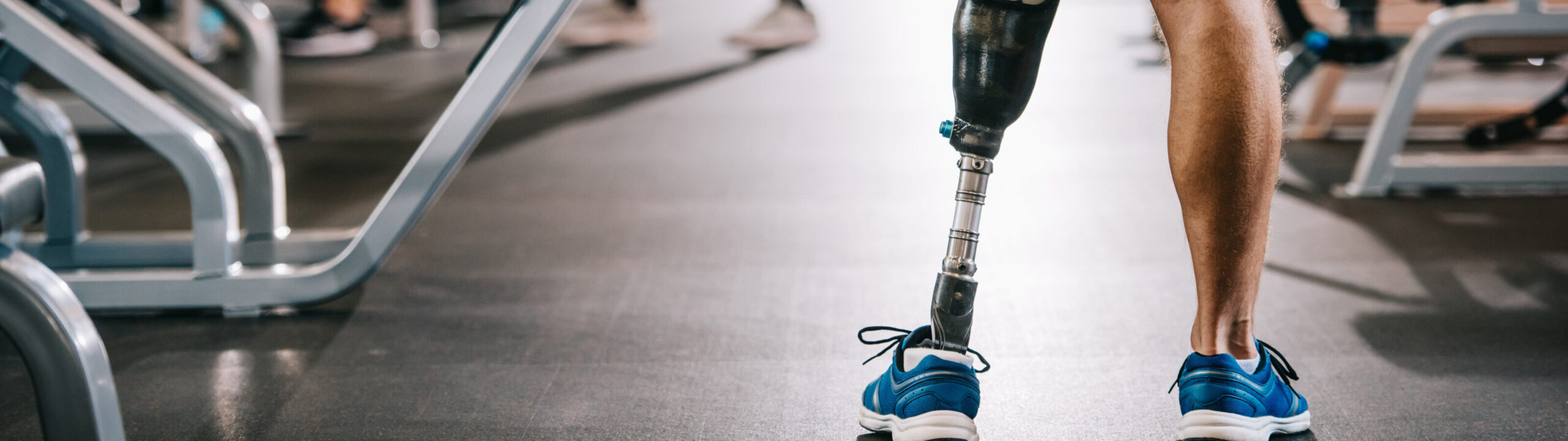 Cropped shot of of sportsman with artificial leg standing at gym 