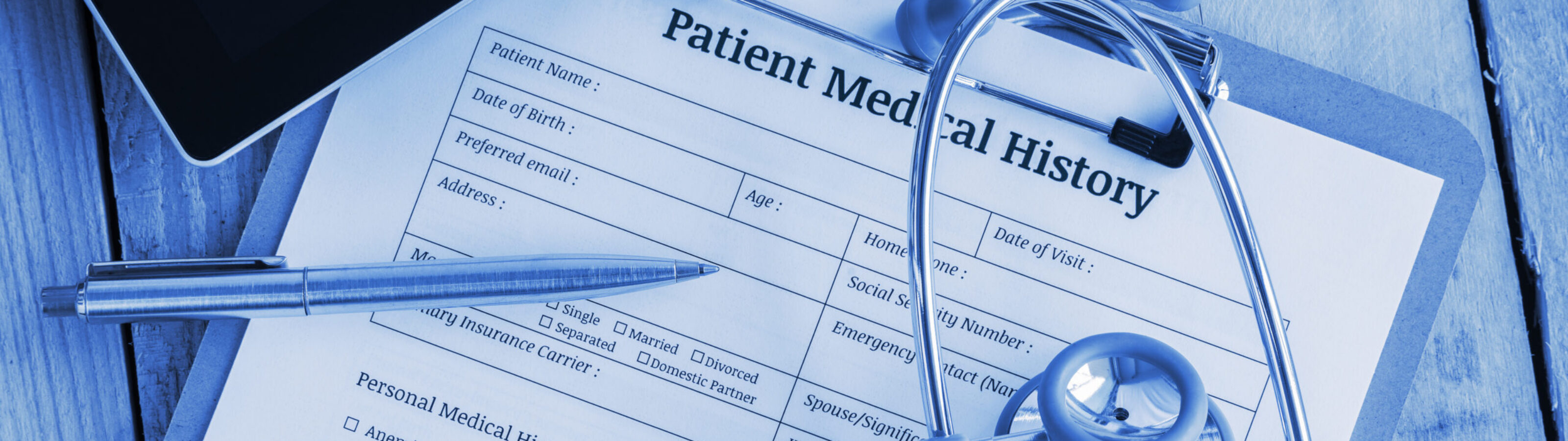 Patient medical history on a clipboard with stethoscope and a blue ballpoint pen, putting on a physician's table. blank form waiting to be filled and reviewed / examined by nurse / clinical assistant. 